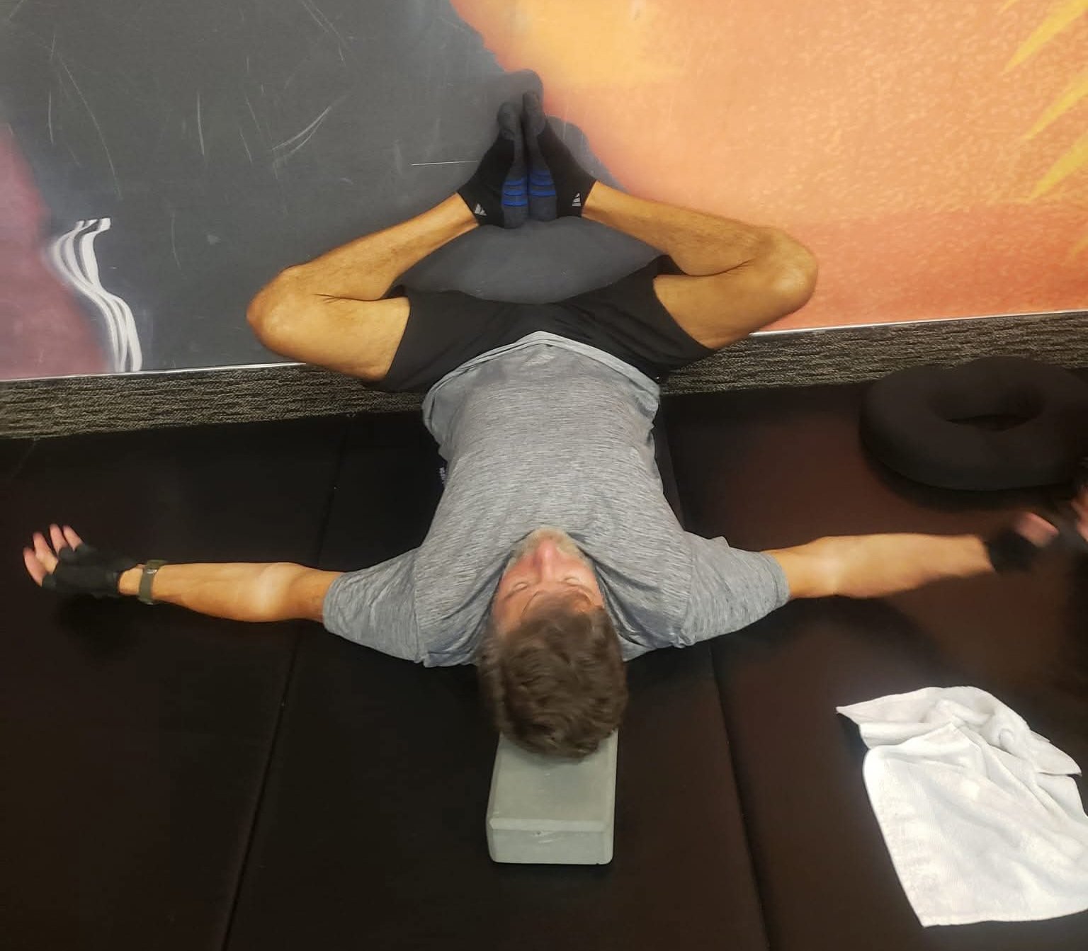 John Kilgore lying on his back in a butterfly stretch with the soles of his feet together