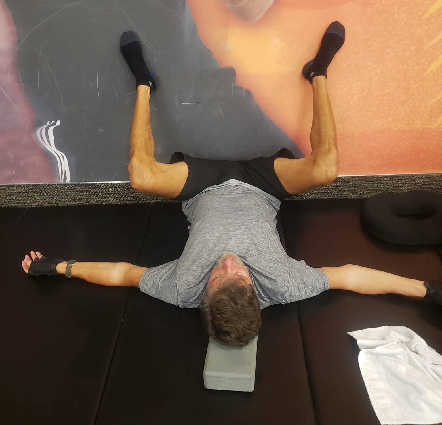 John Kilgore lying on his back in a supported frog stretch with feet against a wall