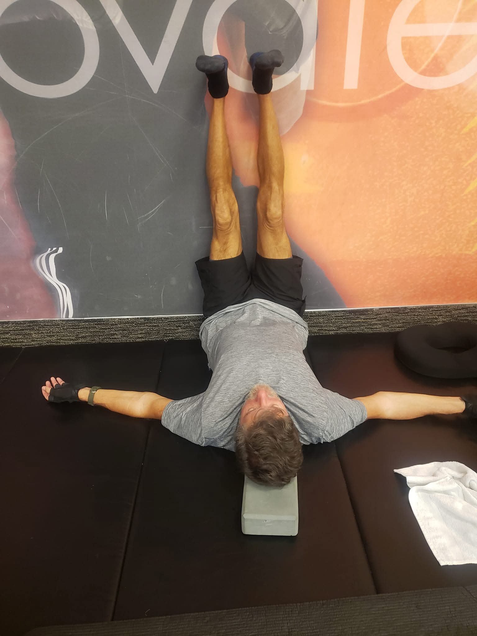 John Kilgore lying on his back with legs extended up a wall and arms outstretched