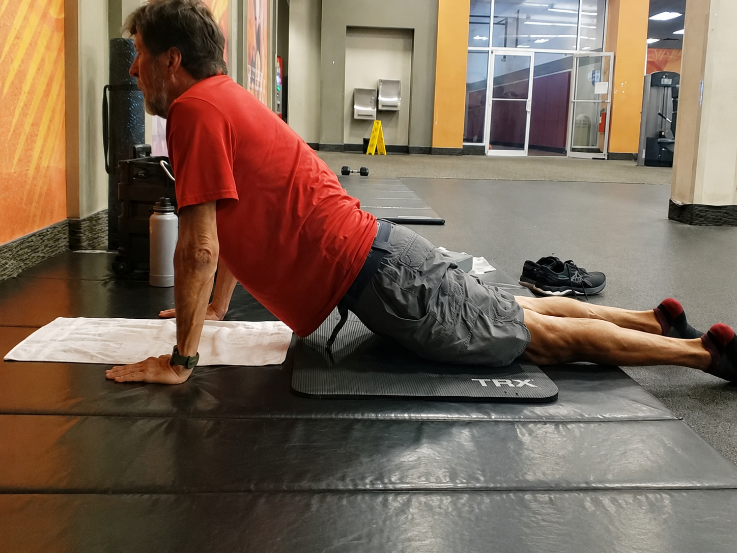 John Kilgore holding a gentle upward-facing stretch on a padded mat