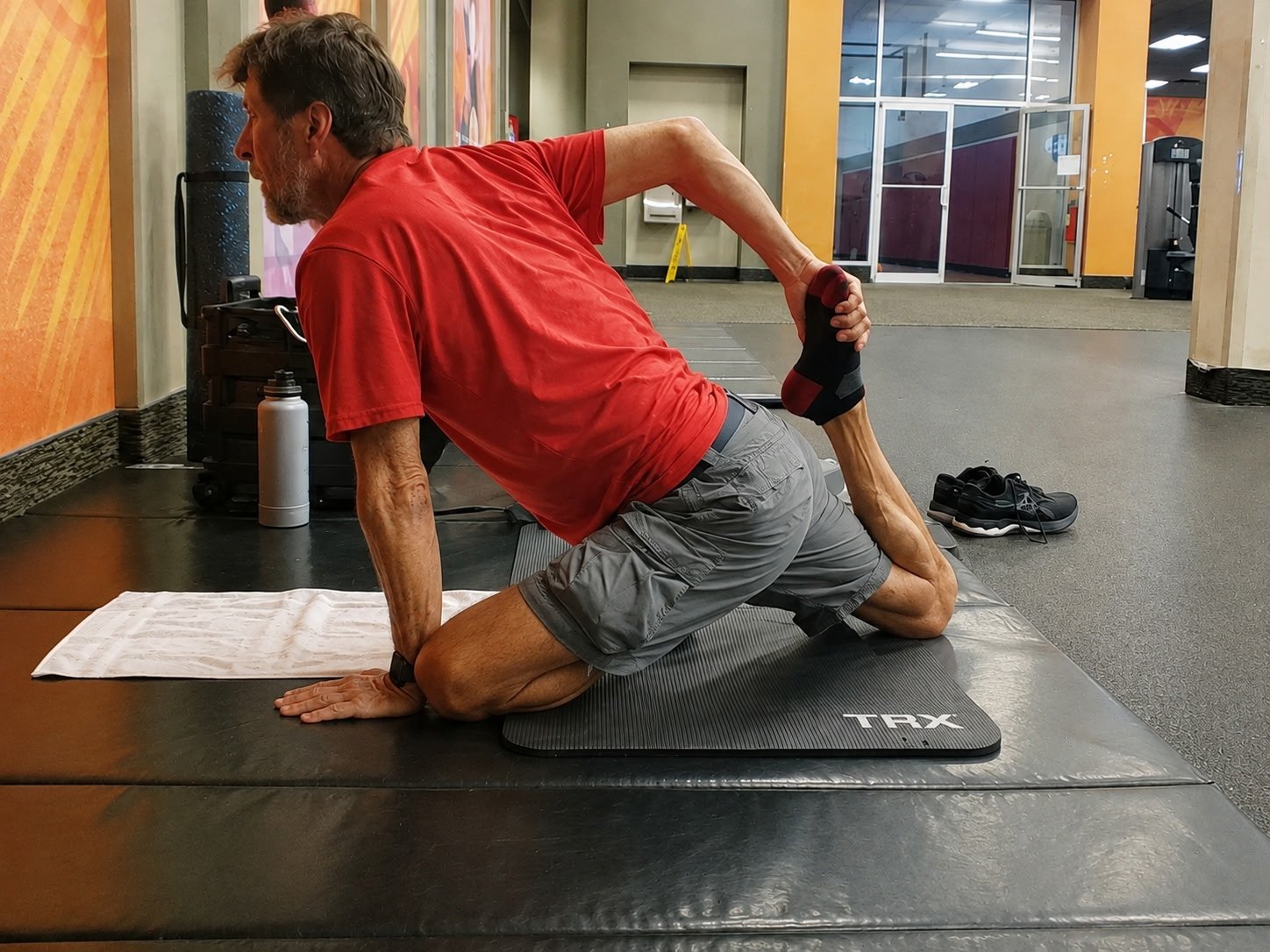 John Kilgore kneeling while holding one foot behind him in a quadriceps stretch