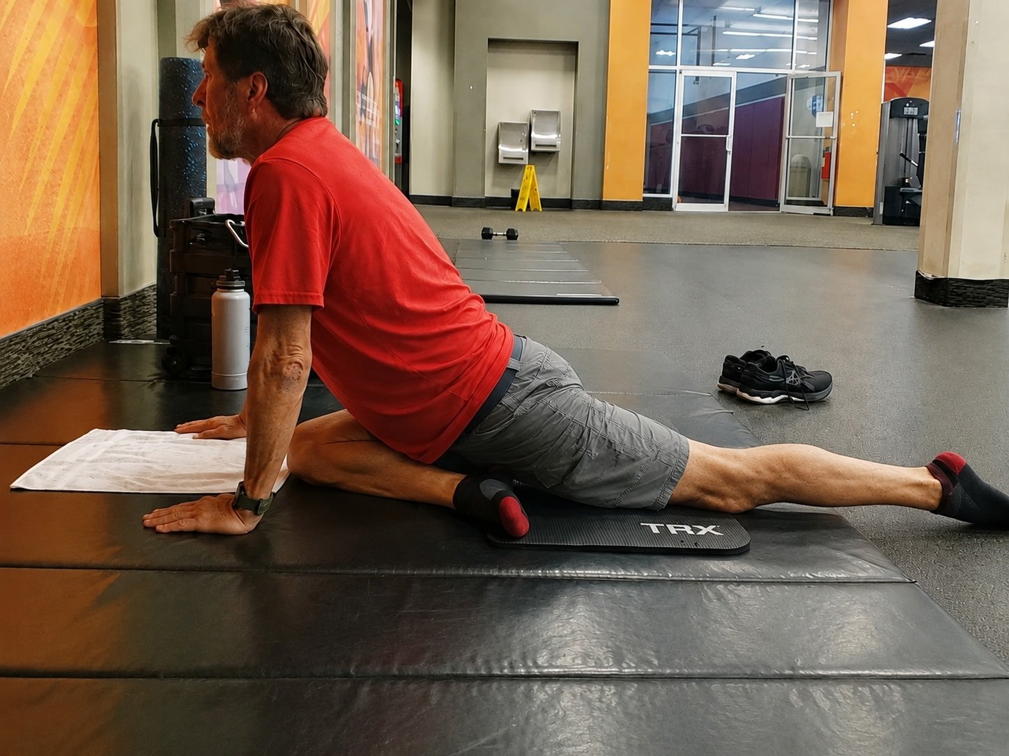 John Kilgore holding a pigeon pose stretch with his torso upright