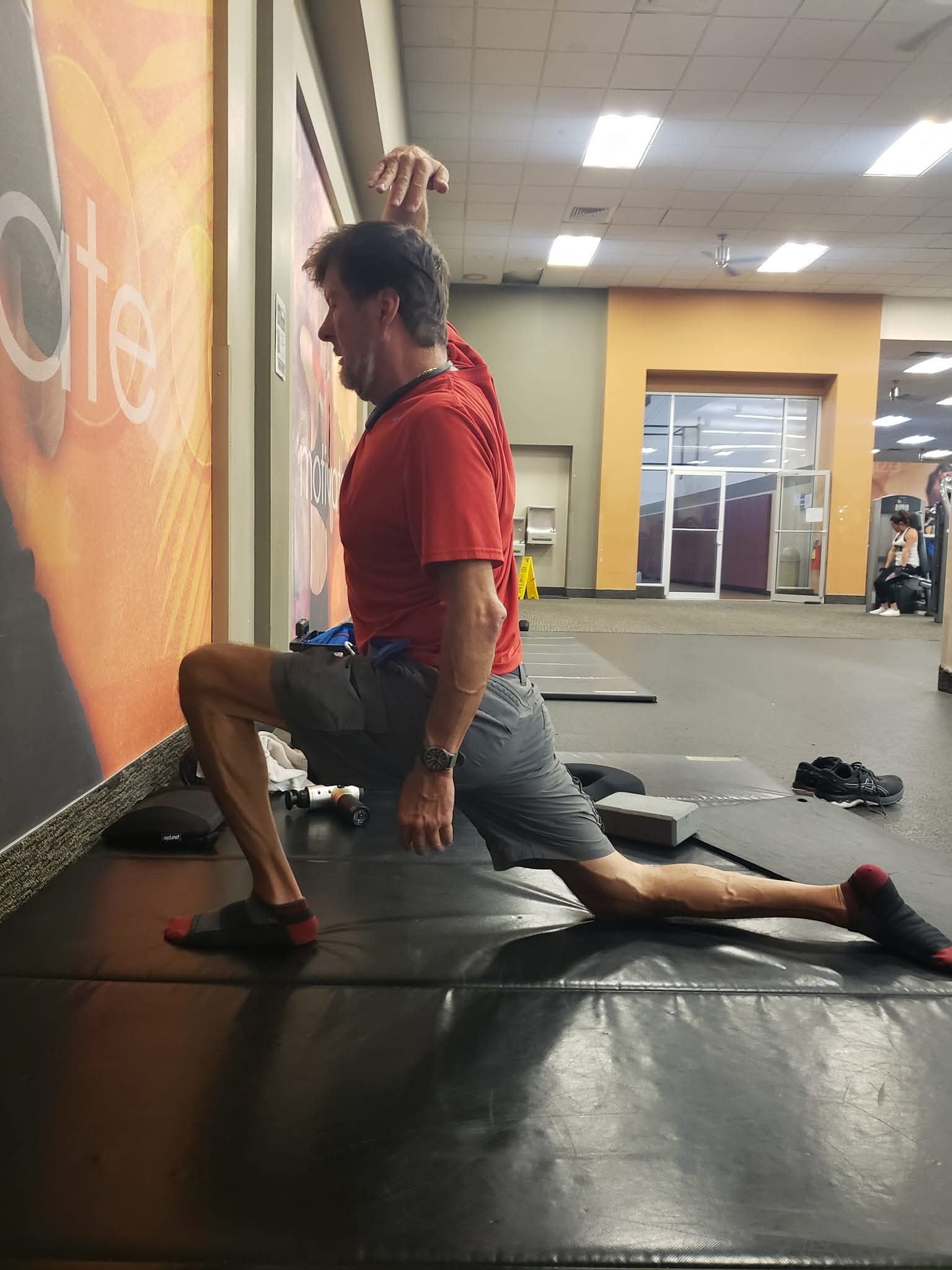 John Kilgore kneeling in a low lunge stretch with one arm raised overhead