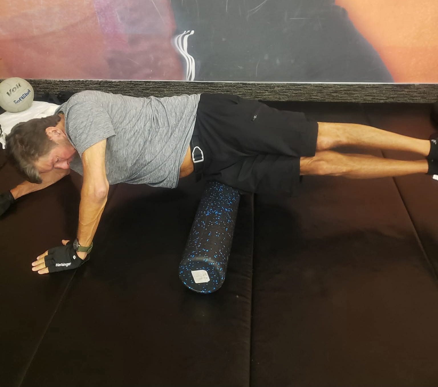 John Kilgore lying on his side with a foam roller positioned beneath his hip