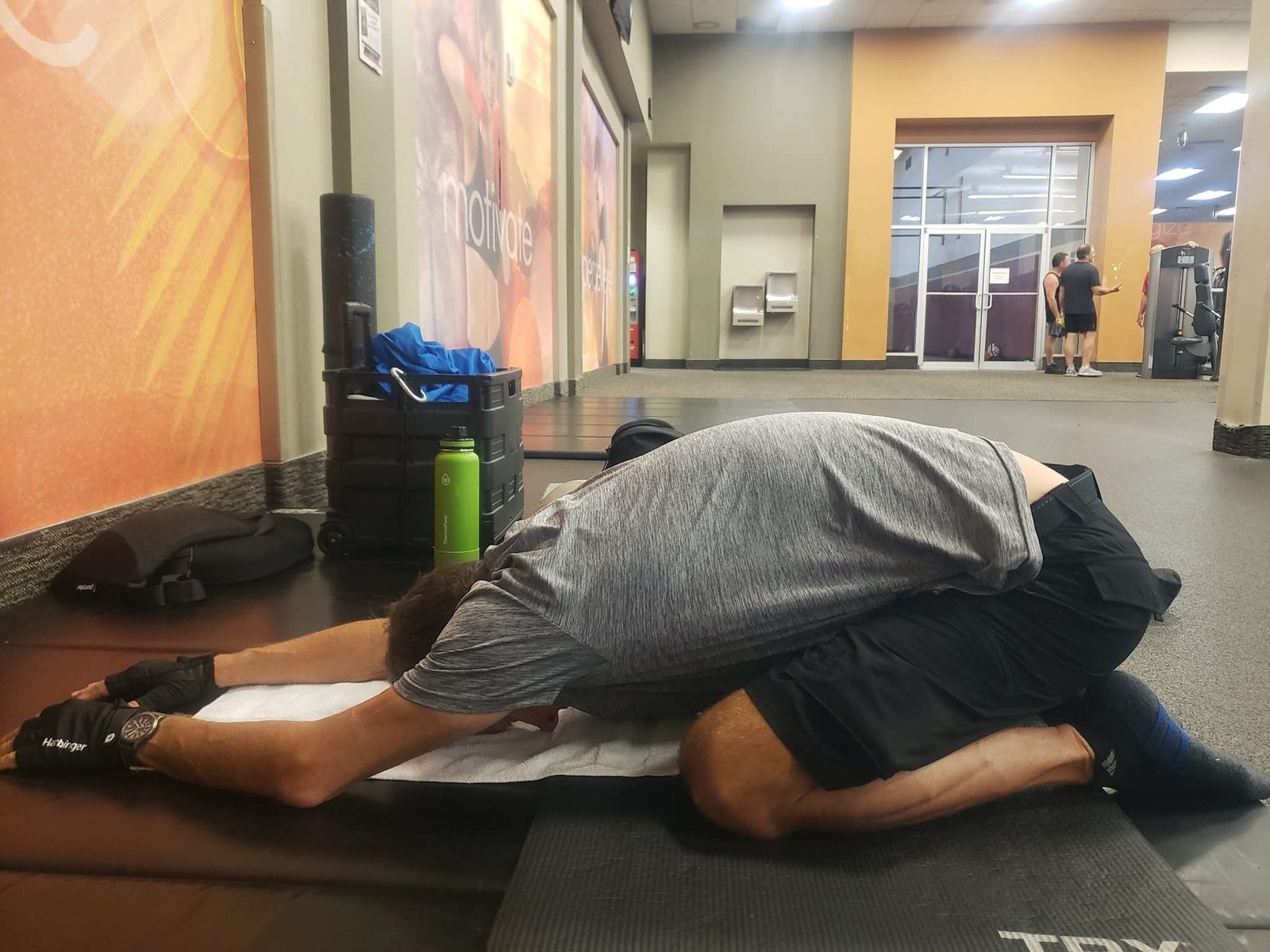John Kilgore kneeling in a child’s pose stretch with arms extended forward